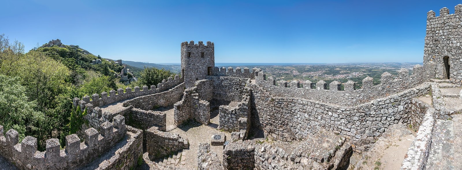 Kartelmuren van het Moorse kasteel slingeren over een beboste heuvel in Sintra