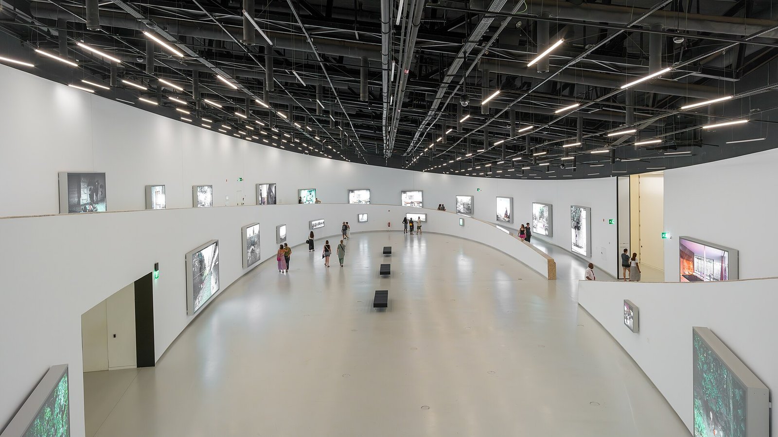 Bezoekers bekijken schilderijen in een rustige zaal van een Lissabons museum