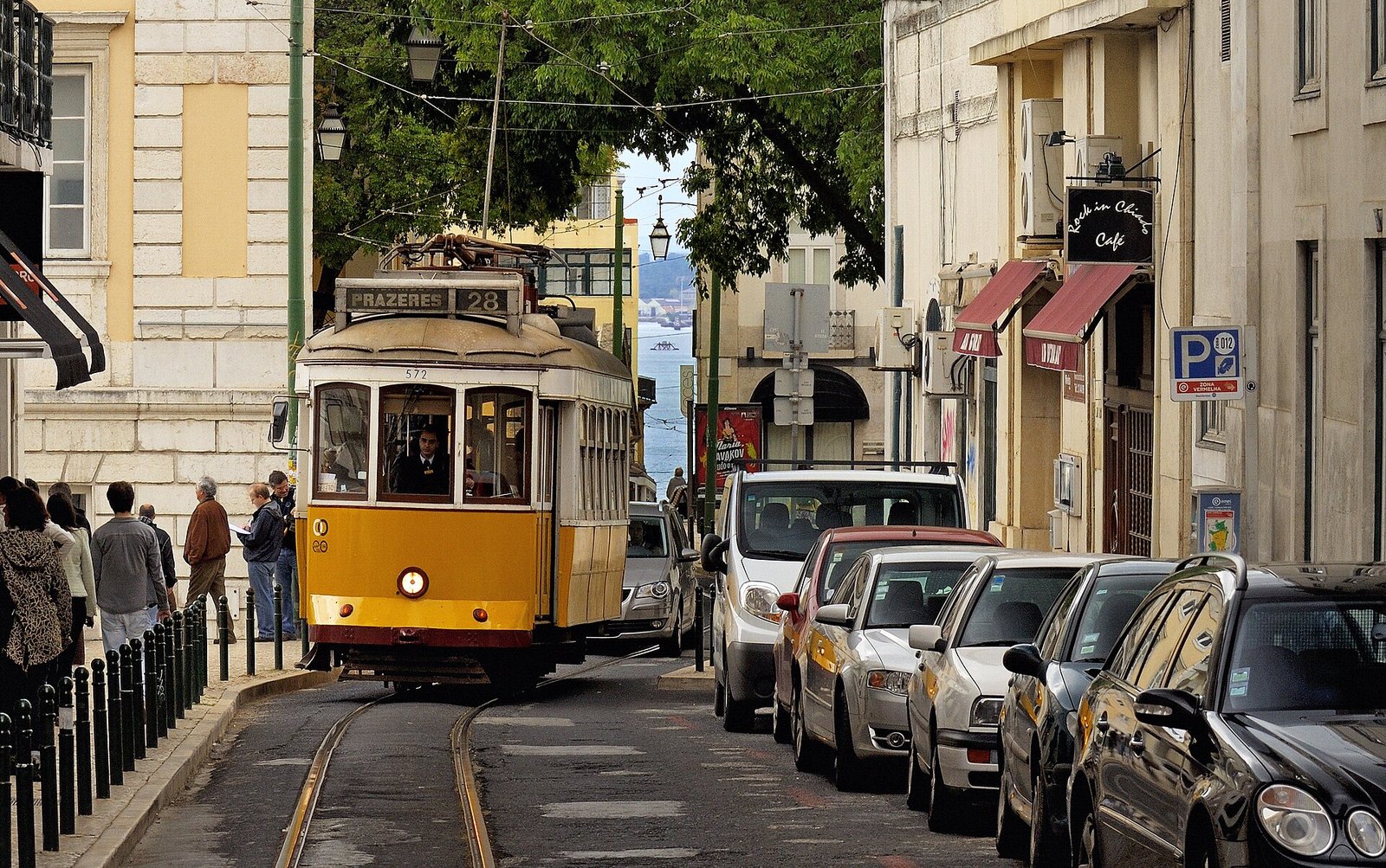 Gele historische tram rijdt door een smalle straat in Lissabon