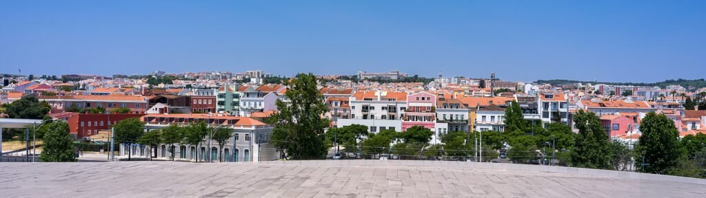 Felle zon boven de daken en lichte gevels van Lissabon