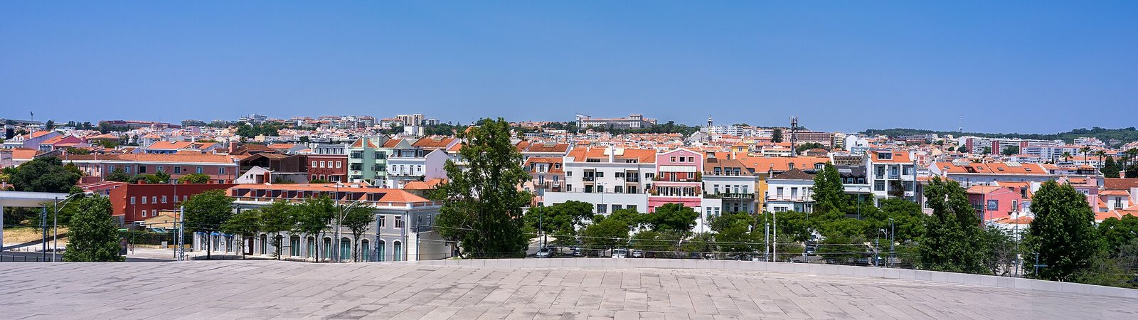 Felle zon boven de daken en lichte gevels van Lissabon