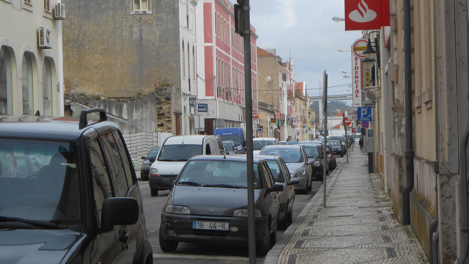 Parkeerautomaat langs een straat vol geparkeerde auto's in Lissabon